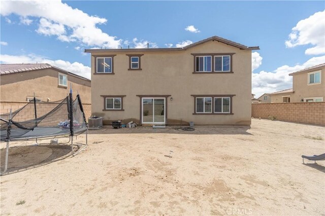 11952 Saxton Way, Victorville, CA 92392 - rear view of property with a trampoline, central AC unit, a fenced backyard, and stucco siding