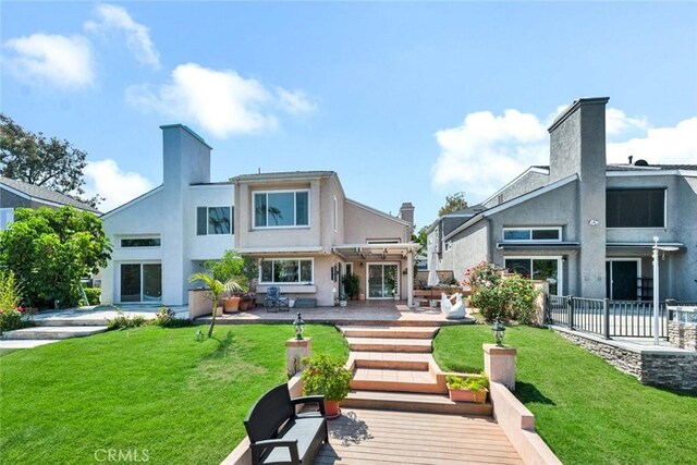 rear view of property with a patio area, a lawn, and stucco siding
