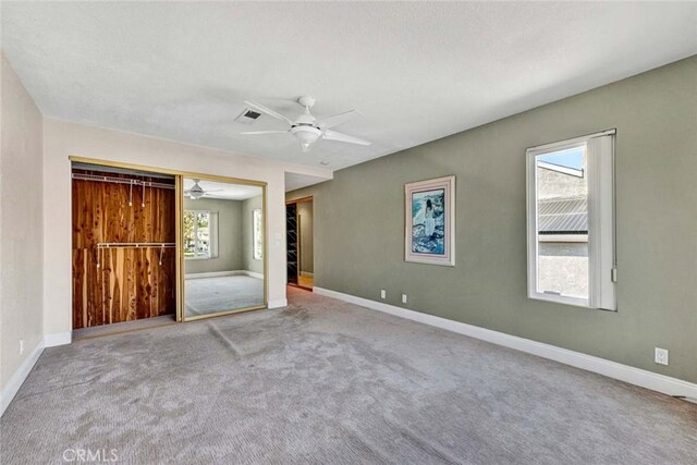 unfurnished bedroom with baseboards, carpet, ceiling fan, and a closet