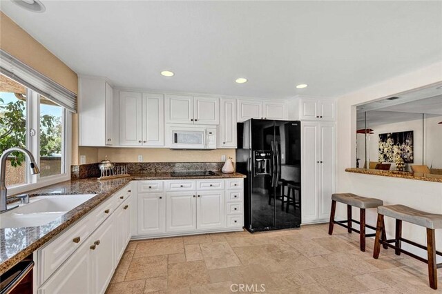 kitchen featuring black appliances, a sink, white cabinets, dark stone counters, and recessed lighting
