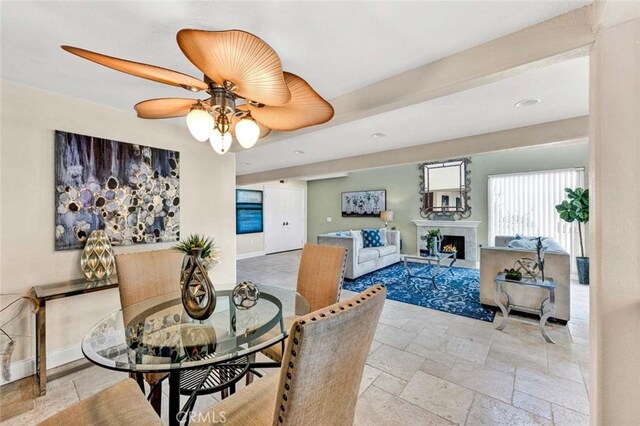 dining room with ceiling fan, stone tile floors, a warm lit fireplace, baseboards, and recessed lighting