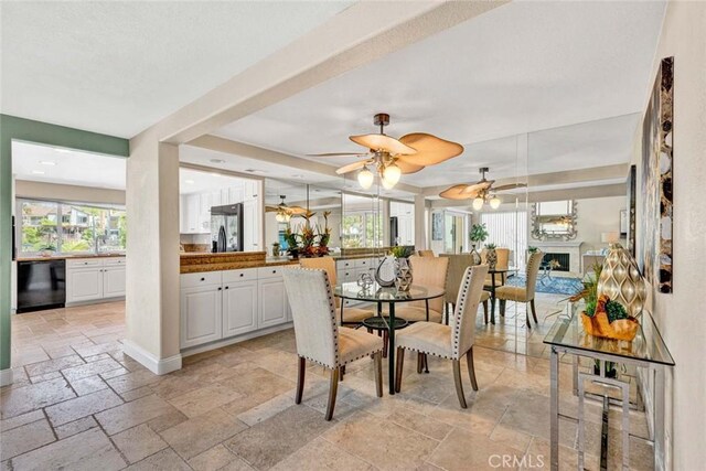 dining space with stone tile floors, ceiling fan, and a fireplace