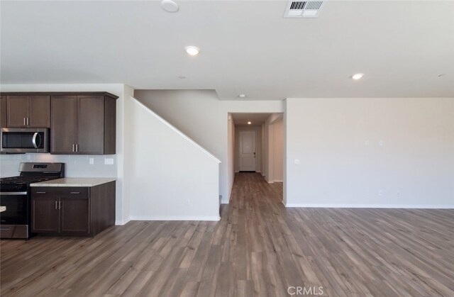 24295 Insignia Dr, Menifee, CA 92584 - kitchen with appliances with stainless steel finishes, open floor plan, wood finished floors, dark brown cabinetry, and light countertops