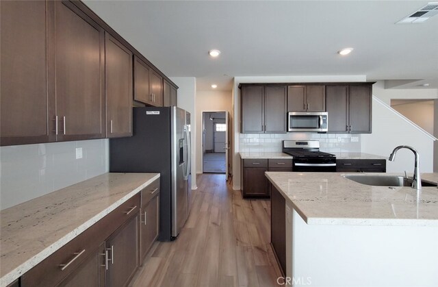 24295 Insignia Dr, Menifee, CA 92584 - kitchen featuring appliances with stainless steel finishes, a sink, backsplash, light wood-style floors, and recessed lighting