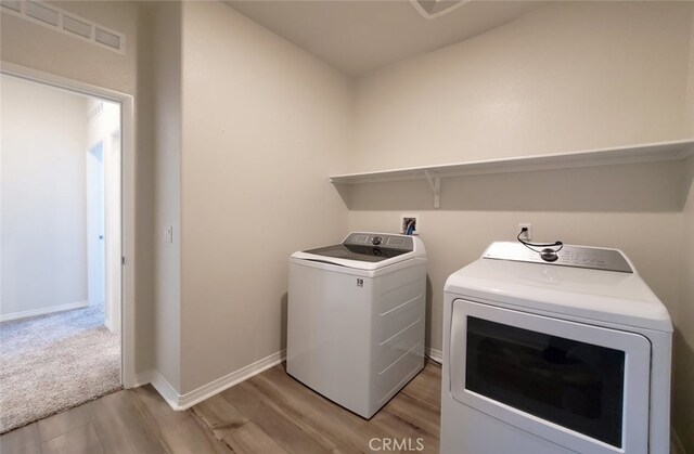 24295 Insignia Dr, Menifee, CA 92584 - laundry room featuring washing machine and dryer, light wood-type flooring, and baseboards