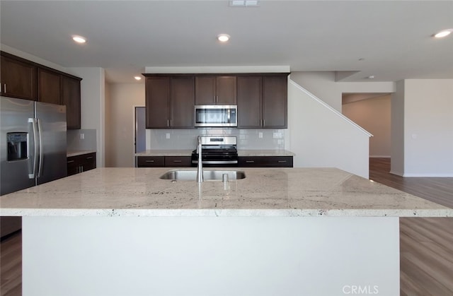 24295 Insignia Dr, Menifee, CA 92584 - kitchen featuring appliances with stainless steel finishes, a center island with sink, dark brown cabinets, backsplash, and recessed lighting