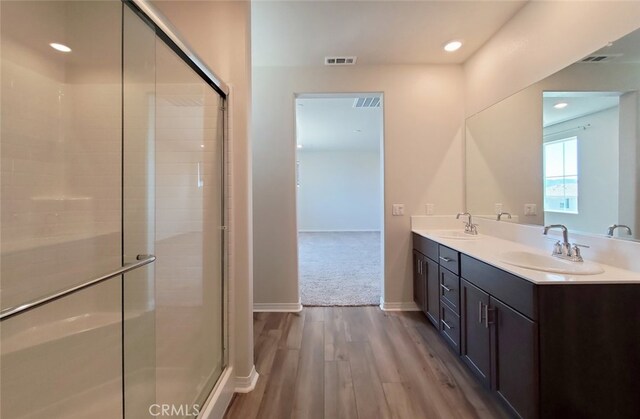 24295 Insignia Dr, Menifee, CA 92584 - bathroom featuring double vanity, wood finished floors, a stall shower, recessed lighting, and baseboards