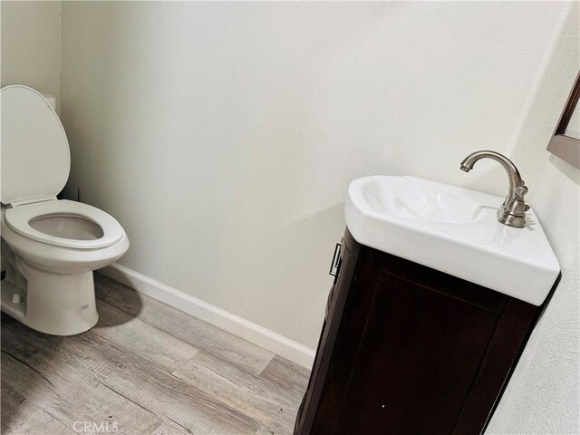 bathroom featuring wood finished floors, toilet, vanity, and baseboards