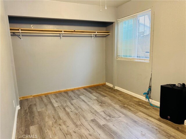 unfurnished bedroom featuring wood finished floors, baseboards, and a closet