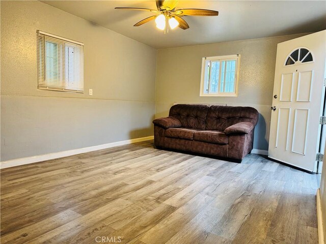 living area featuring wood finished floors, ceiling fan, and baseboards