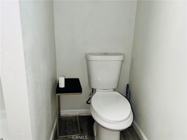 bathroom with baseboards, toilet, and wood finished floors