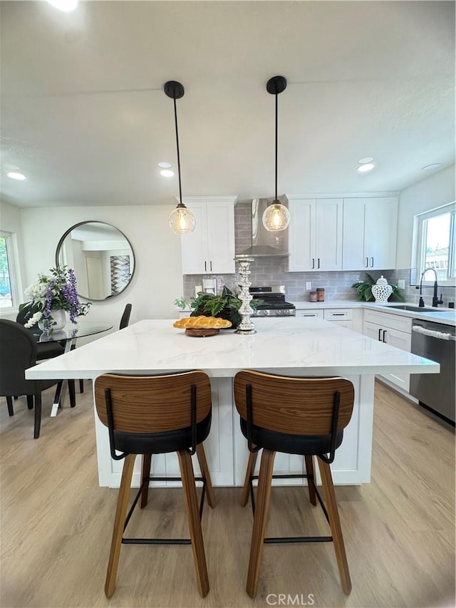 2126 S Fern Ave, Ontario, CA 91762 - kitchen featuring appliances with stainless steel finishes, wall chimney exhaust hood, a center island, white cabinetry, and a sink