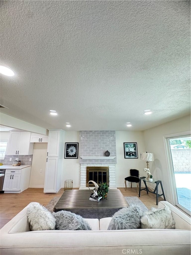 2126 S Fern Ave, Ontario, CA 91762 - living area with a textured ceiling, light wood-style flooring, a brick fireplace, recessed lighting, and baseboards