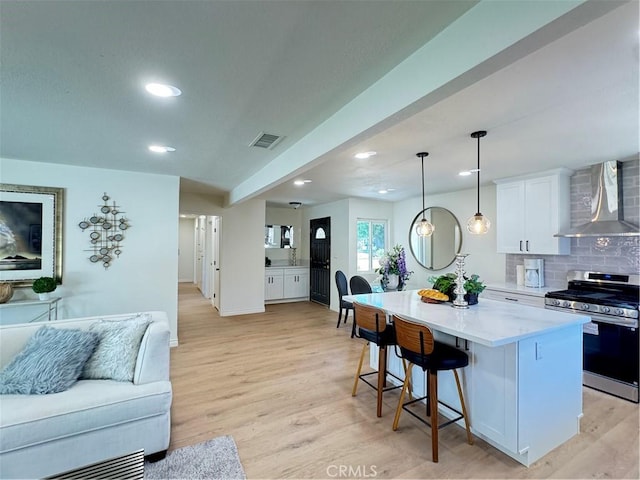 2126 S Fern Ave, Ontario, CA 91762 - kitchen with wall chimney exhaust hood, stainless steel range with gas stovetop, open floor plan, a center island, and light wood-style floors
