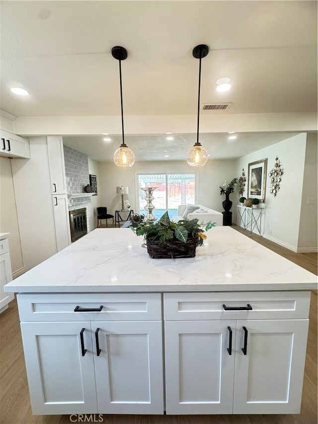 2126 S Fern Ave, Ontario, CA 91762 - kitchen with white cabinetry, light stone counters, a center island, decorative light fixtures, and recessed lighting