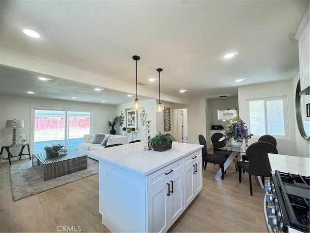 2126 S Fern Ave, Ontario, CA 91762 - kitchen with stainless steel gas range, white cabinets, light wood-style floors, a kitchen island, and open floor plan