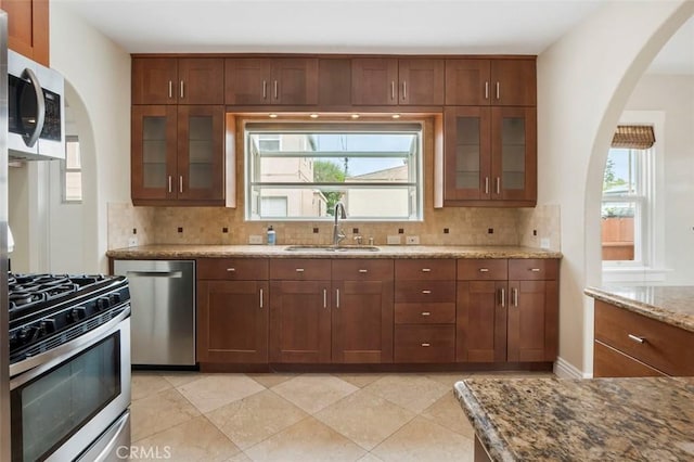 4718 Dawes St, San Diego, CA 92109 - kitchen with a sink, stainless steel appliances, arched walkways, backsplash, and light stone countertops
