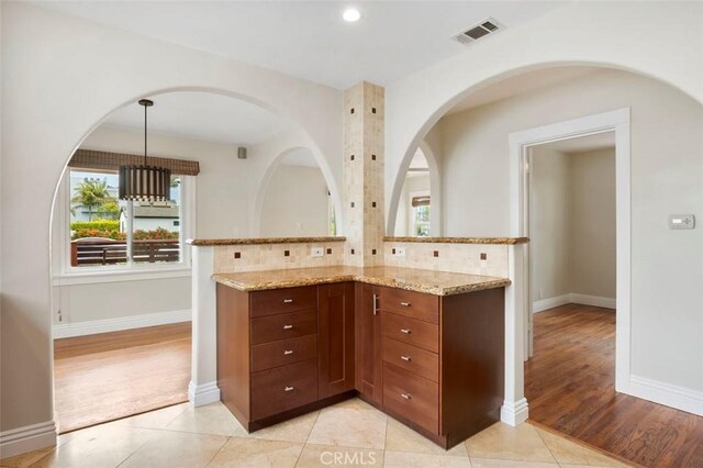 4718 Dawes St, San Diego, CA 92109 - kitchen featuring light stone countertops, pendant lighting, baseboards, brown cabinets, and tasteful backsplash