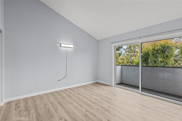 unfurnished room featuring vaulted ceiling, wood finished floors, and baseboards