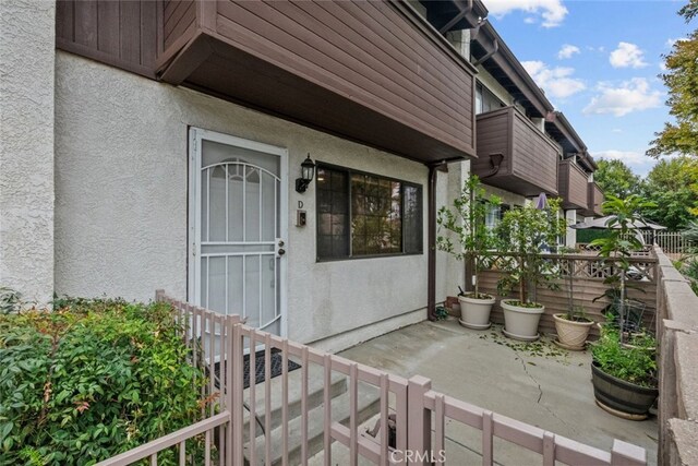 entrance to property featuring stucco siding and fence