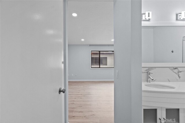 bathroom featuring a sink, wood finished floors, recessed lighting, and baseboards