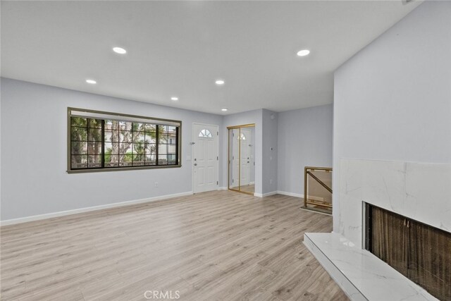 unfurnished living room with recessed lighting, light wood-style floors, and baseboards