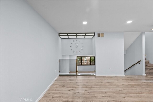 empty room with recessed lighting, wood finished floors, baseboards, and stairway
