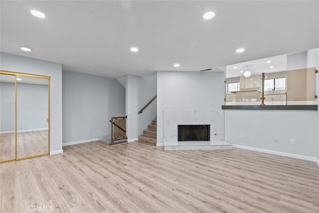 unfurnished living room featuring recessed lighting, wood finished floors, baseboards, and stairway