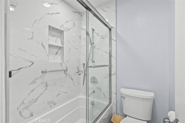 bathroom featuring enclosed tub / shower combo and toilet