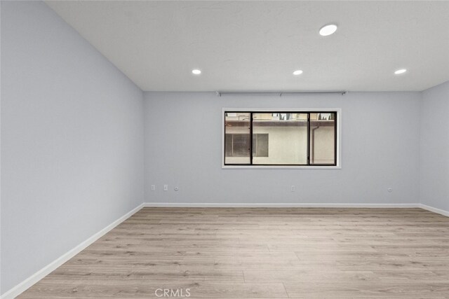 spare room with light wood finished floors, recessed lighting, and baseboards