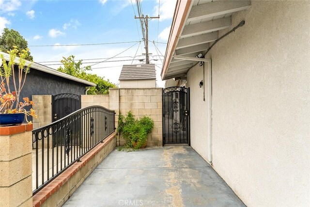 view of side of property with a gate, stucco siding, and fence