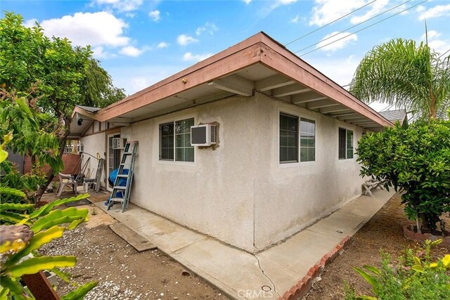 view of property exterior with stucco siding and a wall mounted air conditioner