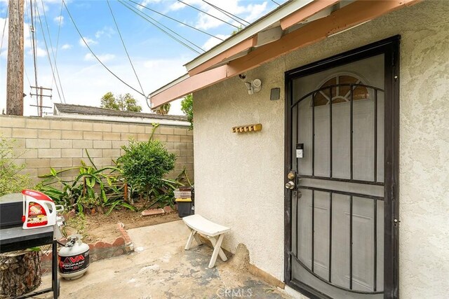 entrance to property featuring stucco siding and fence
