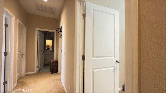 hallway featuring light carpet and baseboards