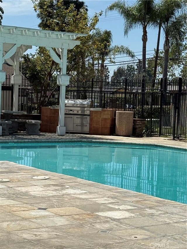 view of pool with fence, area for grilling, and grilling area