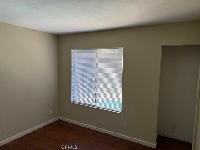 empty room with dark wood-style floors and baseboards