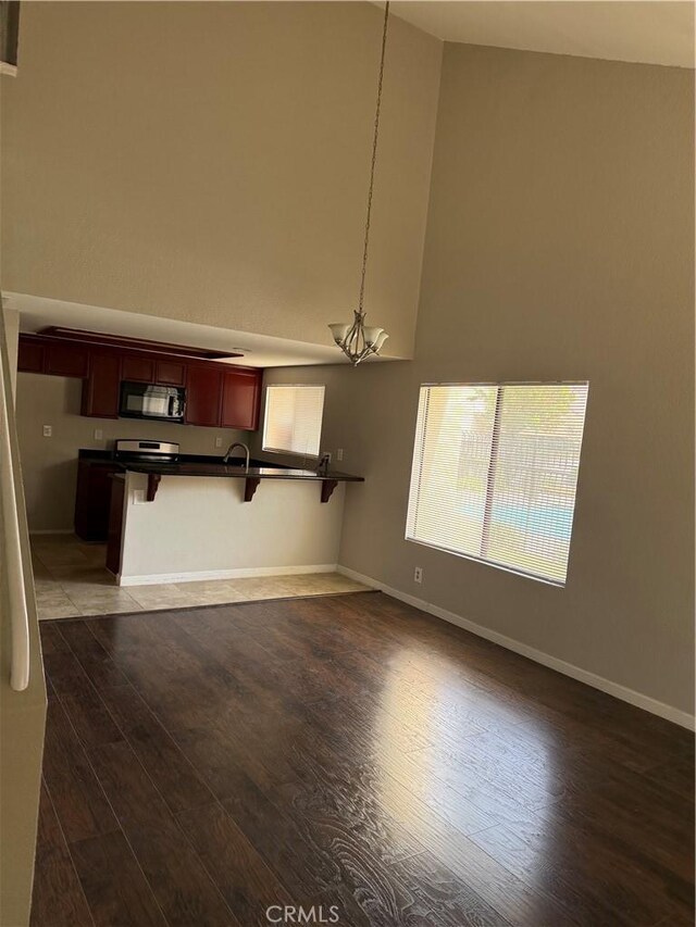 unfurnished dining area featuring dark wood finished floors, baseboards, and a high ceiling