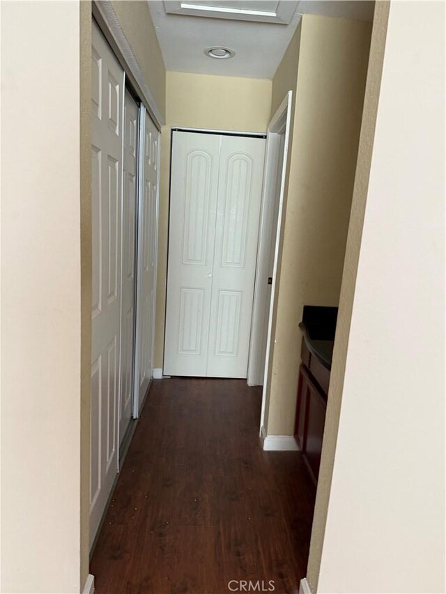 hall with dark wood-type flooring and baseboards
