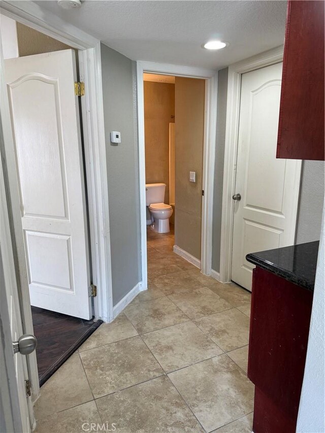 bathroom featuring toilet, baseboards, and tile patterned flooring