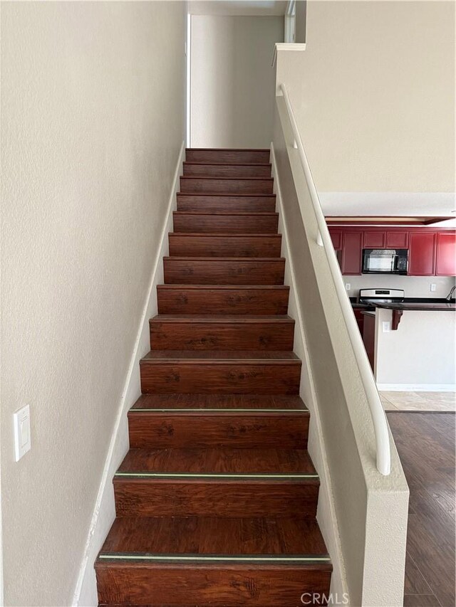 staircase with wood finished floors and a textured wall