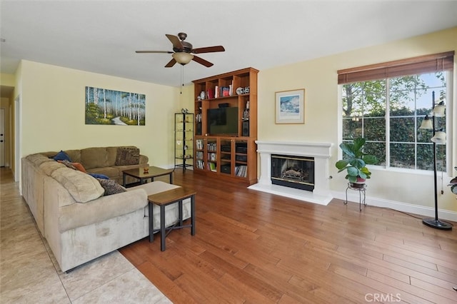 23405 Winslow Pl, Valencia, CA 91354 - living area featuring a ceiling fan, a glass covered fireplace, wood finished floors, and baseboards