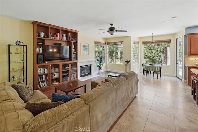 23405 Winslow Pl, Valencia, CA 91354 - living area featuring ceiling fan, light tile patterned floors, baseboards, and a glass covered fireplace