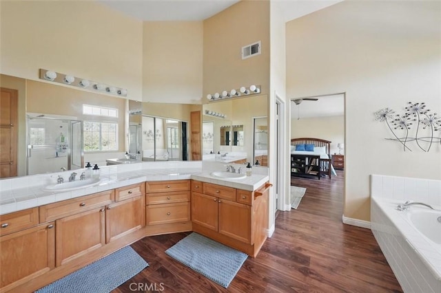23405 Winslow Pl, Valencia, CA 91354 - bathroom featuring a high ceiling, wood finished floors, double vanity, a stall shower, and a garden tub