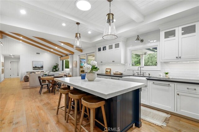kitchen with a sink, decorative backsplash, a kitchen island, light wood finished floors, and recessed lighting