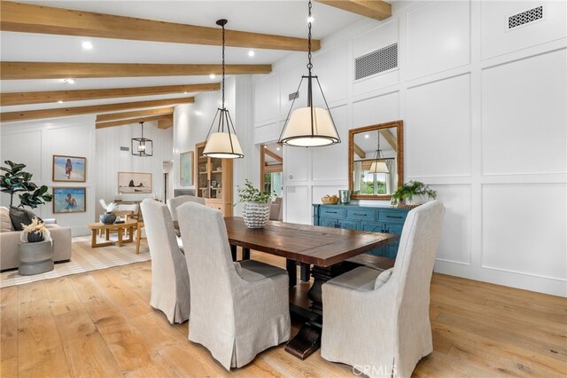 dining area with a decorative wall, light wood-style flooring, beamed ceiling, and recessed lighting