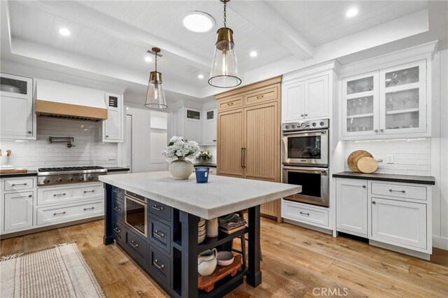 kitchen with white cabinetry, stainless steel appliances, light wood-style flooring, beamed ceiling, and wooden ceiling