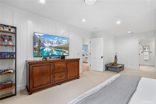 bedroom with light carpet, recessed lighting, and a decorative wall
