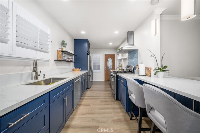kitchen with stainless steel appliances, blue cabinetry, a sink, wall chimney range hood, and open shelves