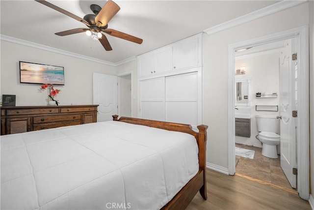 bedroom with crown molding, light wood finished floors, a closet, ensuite bath, and a ceiling fan