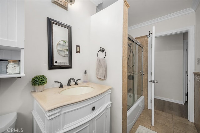 bathroom featuring vanity, toilet, bath / shower combo with glass door, crown molding, and tile patterned floors